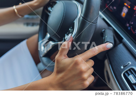 Woman's hand switches the lobes of the gear selector on the steering wheel. Hand is switching car gear lever, close up shot of a manual gear changing paddle on a car's steering wheel. 78386770