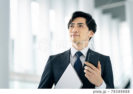 オフィスでスマホを操作するスーツ姿のビジネスマン 78389888