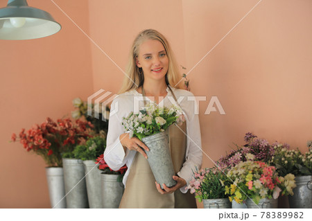 Beautiful blonde hair girl standing with confidence in front of flower in open retails flora shop. Small business owner concept. Beautiful blonde hair girl standing with confidence in front of flower in open retails flora shop. Small business owner concept. 78389982