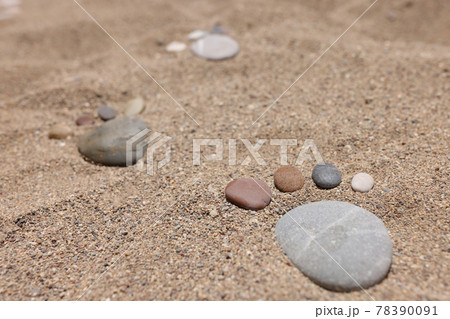 Feet are made of stones on beach sand. 78390091