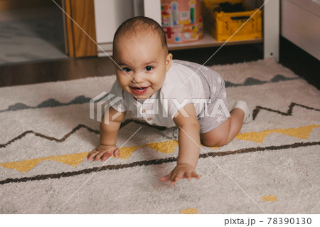 Little child learning to crawl. Very sweet baby boy crawling on the floor at home 78390130