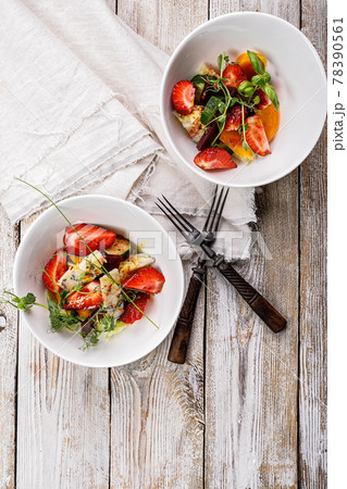 Delicious summer salad. Salad with fresh strawberries, baked beets, yellow tomatoes, dor blue cheese and herbs in a white bowl on a light rustic background. Vertical shot. Summerfood. Copy space Delicious summer salad. Salad with fresh strawberries, baked beets, yellow tomatoes, dor blue cheese and herbs in a white bowl on a light rustic background. Vertical shot. Summerfood. Copy space 78390561