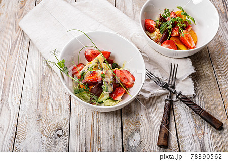 Delicious summer salad. Salad with fresh strawberries, baked beets, yellow tomatoes, dor blue cheese and herbs in a white bowl on a light rustic background. Top view. Copy space. Summerfood Delicious summer salad. Salad with fresh strawberries, baked beets, yellow tomatoes, dor blue cheese and herbs in a white bowl on a light rustic background. Top view. Copy space. Summerfood 78390562