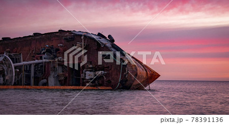 Sunrise time photo of rusty wreaked ship on the purple sea surface 78391136