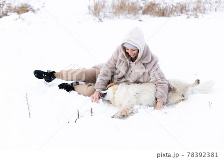 Young beautiful woman and her golden retriever dog having fun in winter. 78392381