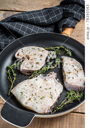 Fresh raw wolffish fillet steaks in a pan with herbs. wooden background. Top view Fresh raw wolffish fillet steaks in a pan with herbs. wooden background. Top view 78393563