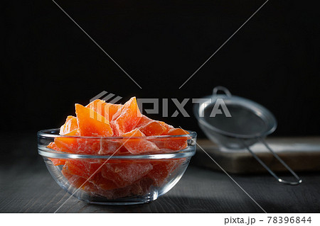 Natural farm homemade candied pumpkin fruits sprinkled with powdered sugar in a glass bowl on a wooden table 78396844