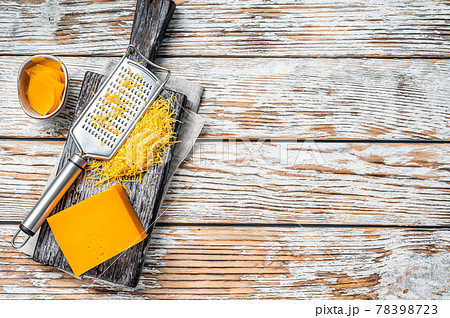 Grated Cheddar Cheese on a wooden cutting board. White wooden background. Top view. Copy space Grated Cheddar Cheese on a wooden cutting board. White wooden background. Top view. Copy space 78398723