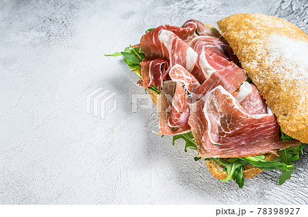 Prosciutto parma ham sandwich on ciabatta bread with arugula. White background. Top view. Copy space Prosciutto parma ham sandwich on ciabatta bread with arugula. White background. Top view. Copy space 78398927