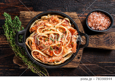 Trendy baked Feta pasta with Oven roasted tomatoes and cheese in a pan. Dark wooden background. Top view 78398944