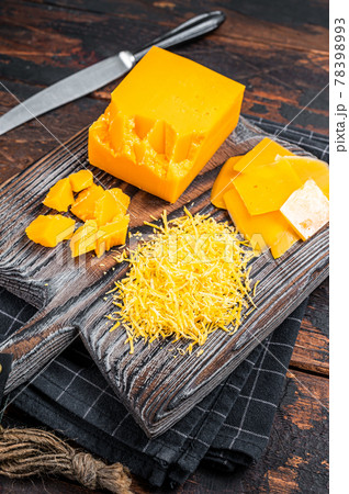 Grated and diceded Cheddar Cheese on a wooden chopping board. Dark wooden background. Top view 78398993