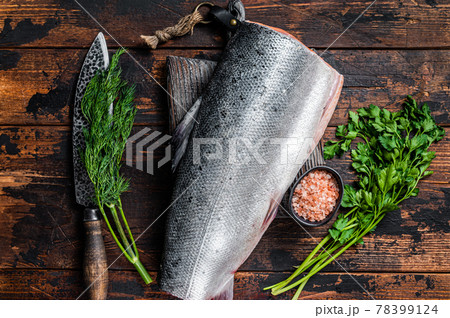 Big piece of Raw cut salmon fish on a wooden cutting board with chef knife. Dark Wooden background. Top view Big piece of Raw cut salmon fish on a wooden cutting board with chef knife. Dark Wooden background. Top view 78399124