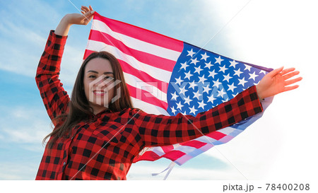 Young millennial brunette woman holding The National Flag of USA. American Flag. Tourist traveler or patriotism. Immigrant in free country. July 4th Independence Day. Caucasian Young millennial brunette woman holding The National Flag of USA. American Flag. Tourist traveler or patriotism. Immigrant in free country. July 4th Independence Day. Caucasian 78400208