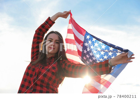 Young millennial brunette woman holding The National Flag of USA. American Flag. Tourist traveler or patriotism. Immigrant in free country. July 4th Independence Day. Caucasian Young millennial brunette woman holding The National Flag of USA. American Flag. Tourist traveler or patriotism. Immigrant in free country. July 4th Independence Day. Caucasian 78400211