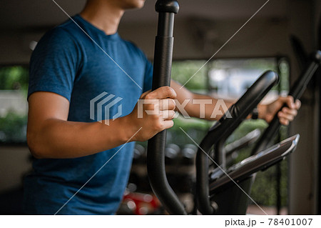 Training gym concept a male teenager doing cardio workout on cycling machine in the gym as his healthy routine Training gym concept a male teenager doing cardio workout on cycling machine in the gym as his healthy routine 78401007