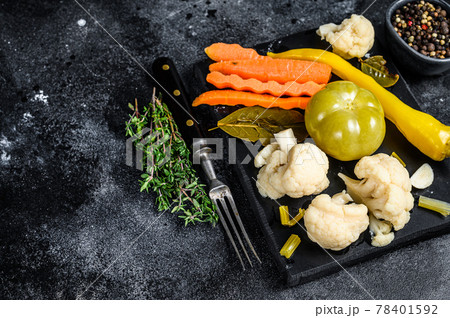 Fresh preserves vegetables, homemade delicious pickles on a marble board. Black background. Top view. Copy space Fresh preserves vegetables, homemade delicious pickles on a marble board. Black background. Top view. Copy space 78401592