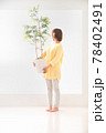 観葉植物を持って葉の緑を見つめる笑顔の若い女性 78402491