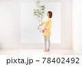 観葉植物を持って葉の緑を見つめる笑顔の若い女性 78402492