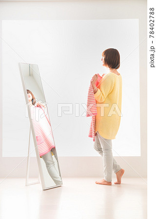 ピンク色のボーダー柄の洋服を鏡の前で体に合わせてみる若い女性 ピンク色のボーダー柄の洋服を鏡の前で体に合わせてみる若い女性 78402788
