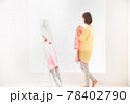 ピンク色のボーダー柄の洋服を鏡の前で体に合わせてみる若い女性 78402790
