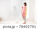 ピンク色のボーダー柄の洋服を鏡の前で体に合わせてみる若い女性 78402791