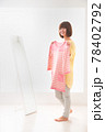 ピンク色のボーダー柄の洋服を鏡の前で体に合わせてみる若い女性 78402792