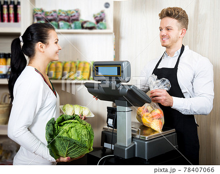 Man seller helping customer to weigh purchases 78407066