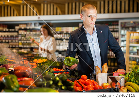 Young confident man selects fresh vegetables in the supermarket 78407119