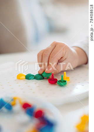 The child sticks the mosaic into the shape with his fingers 78408618