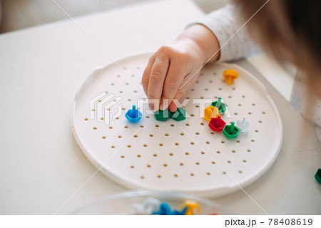 A toddler assembles a mosaic from small parts 78408619