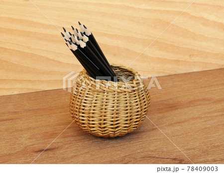 Pencils tied with a rope of straw and place in a container that is made from woven rattan. 78409003