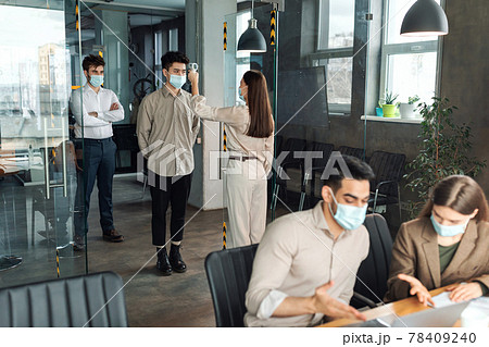 Worker with contactless thermometer measuring temperature of multiracial employees Worker with contactless thermometer measuring temperature of multiracial employees 78409240