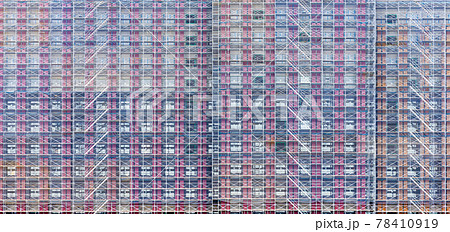 Side view of building under construction covered by net. 78410919