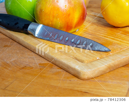 Knife, green apples and yellow quince with water drops on a wooden cutting board 78412306