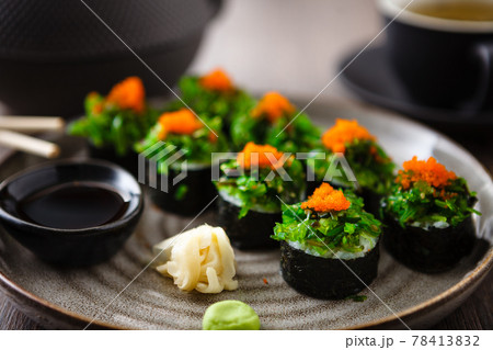 Sushi maki rolls with crab, seaweed salad and flying fish roe on a plate with chopsticks, soy sauce, wasabi and ginger. Japanese traditional seafood served for lunch in modern gourmet restaurant Sushi maki rolls with crab, seaweed salad and flying fish roe on a plate with chopsticks, soy sauce, wasabi and ginger. Japanese traditional seafood served for lunch in modern gourmet restaurant 78413832