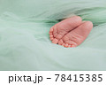 Baby's feet under a green blanket 78415385