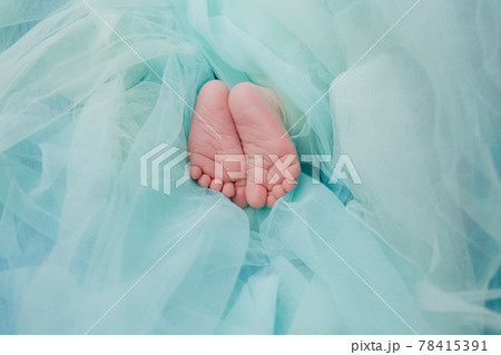 Baby's feet under a green blanket Baby's feet under a green blanket 78415391