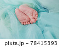 Baby's feet under a green blanket 78415393