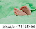 Baby's feet under a green blanket 78415400