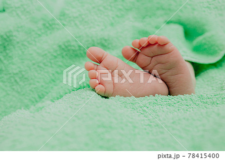 Baby's feet under a green blanket 78415400
