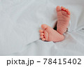 Baby's feet under a white blanket 78415402