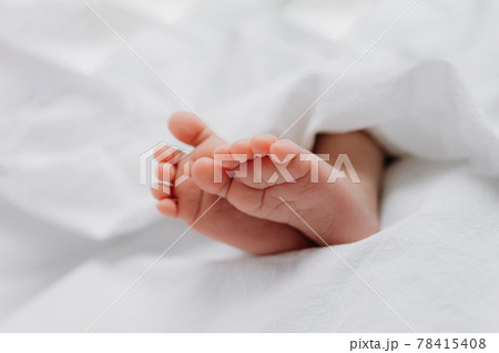 Baby's feet under a white blanket 78415408