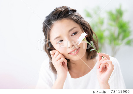 白背景で1輪の花を持って微笑む若い女性のポートレート 白背景で1輪の花を持って微笑む若い女性のポートレート 78415906