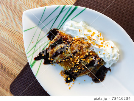 Thin pancake with chocolate, whipped cream, nut crumbs 78416284