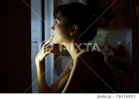 深夜に食事をする若い女性 78416655
