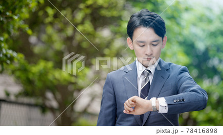 屋外で腕時計を見るビジネスマン 78416898