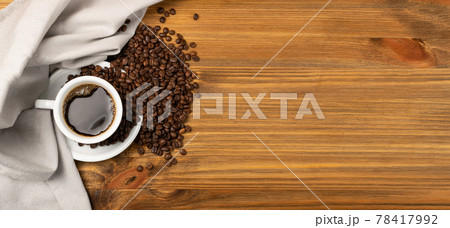 Hot coffee cup and coffee beans on brown background top view Hot coffee cup and coffee beans on brown background top view 78417992