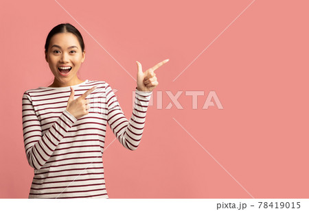 Excited Young Asian Female Pointing Aside At Copy Space With Two Hands 78419015