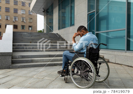 Upset handicapped black man in wheelchair in front of stairs without ramp, having no possibility to enter building Upset handicapped black man in wheelchair in front of stairs without ramp, having no possibility to enter building 78419079