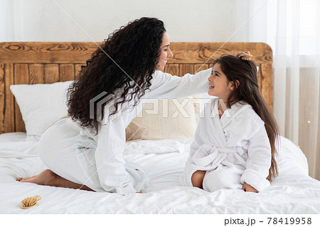 Loving mother brushing her little daughter long hair Loving mother brushing her little daughter long hair 78419958